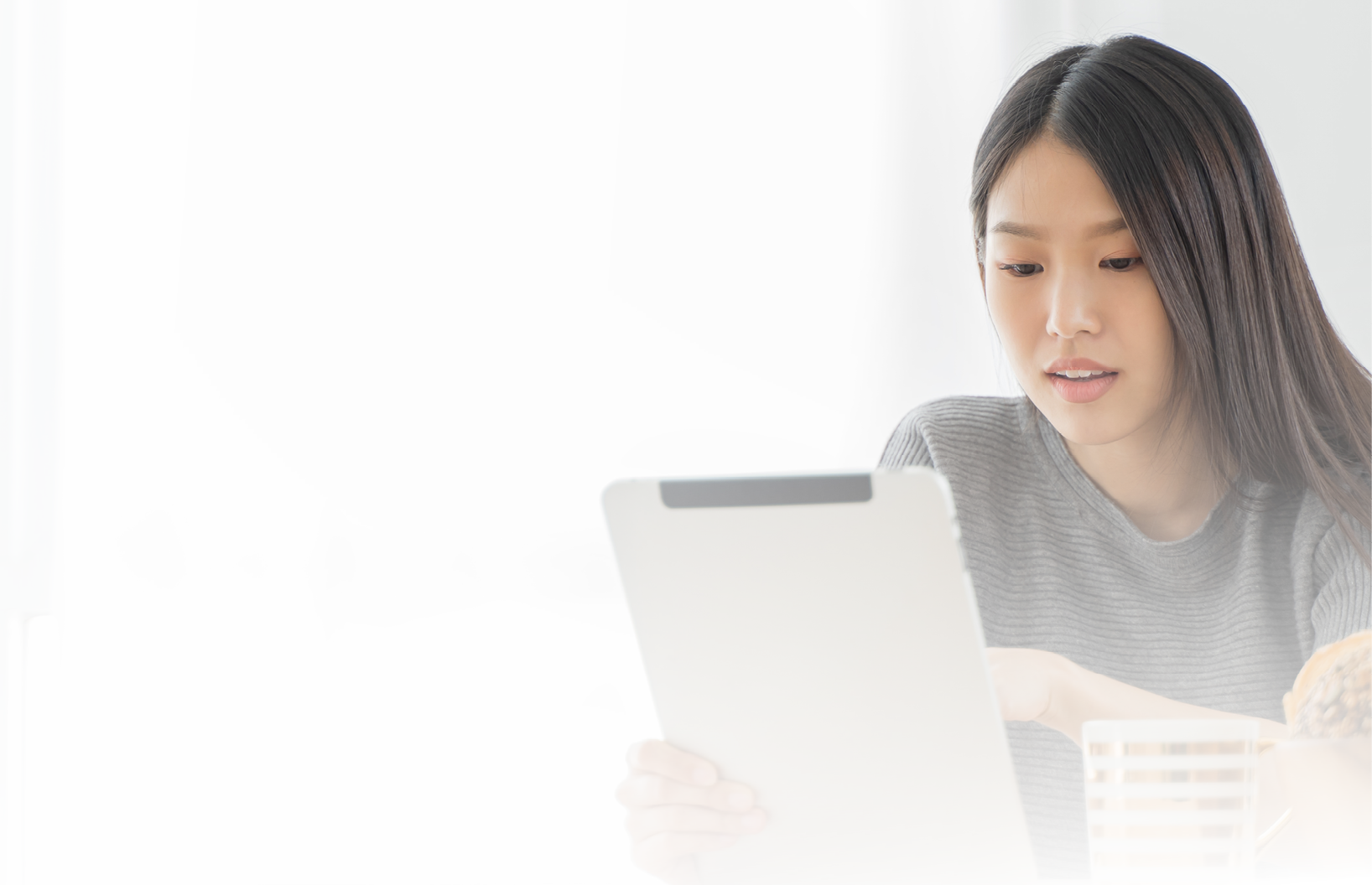 Young Asian woman using tablet at home and having breakfast in the morning  She reading on tablet 