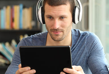 Serious man using tablet and headphones in a coffee shop