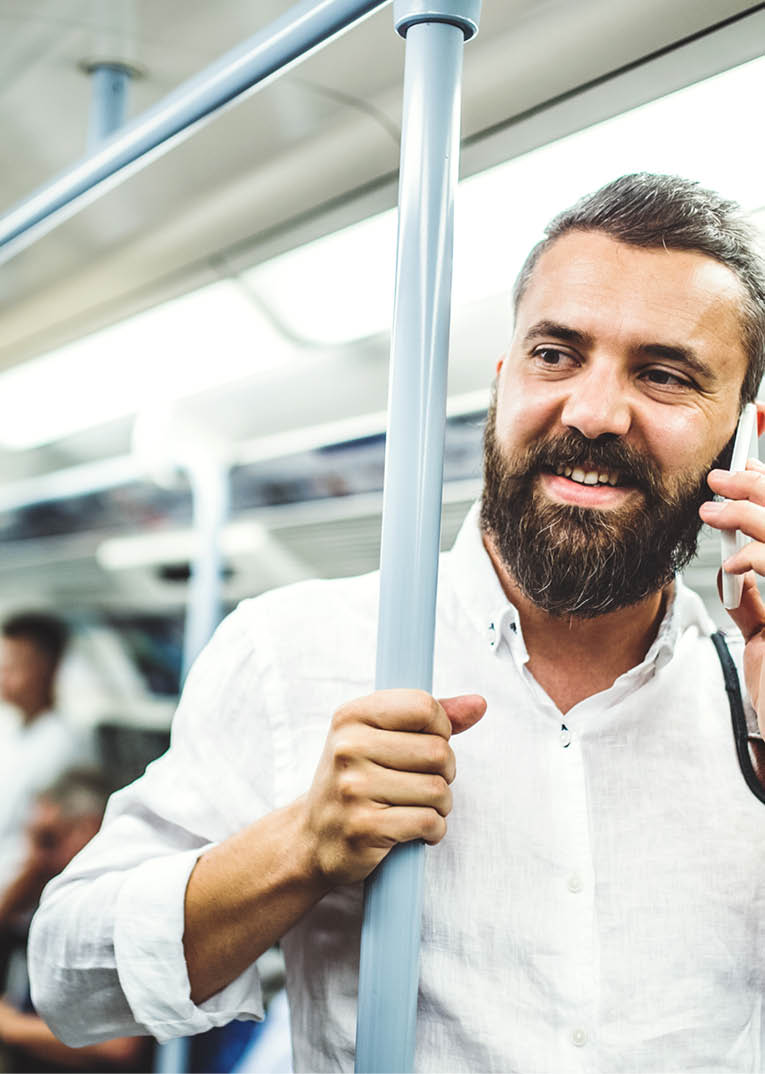 Hipster businessman with smartphone standing inside the subway in the city, travelling to work and making a phone call 
