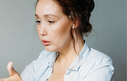 Adult brunette woman reads terrible news at opened laptop at table